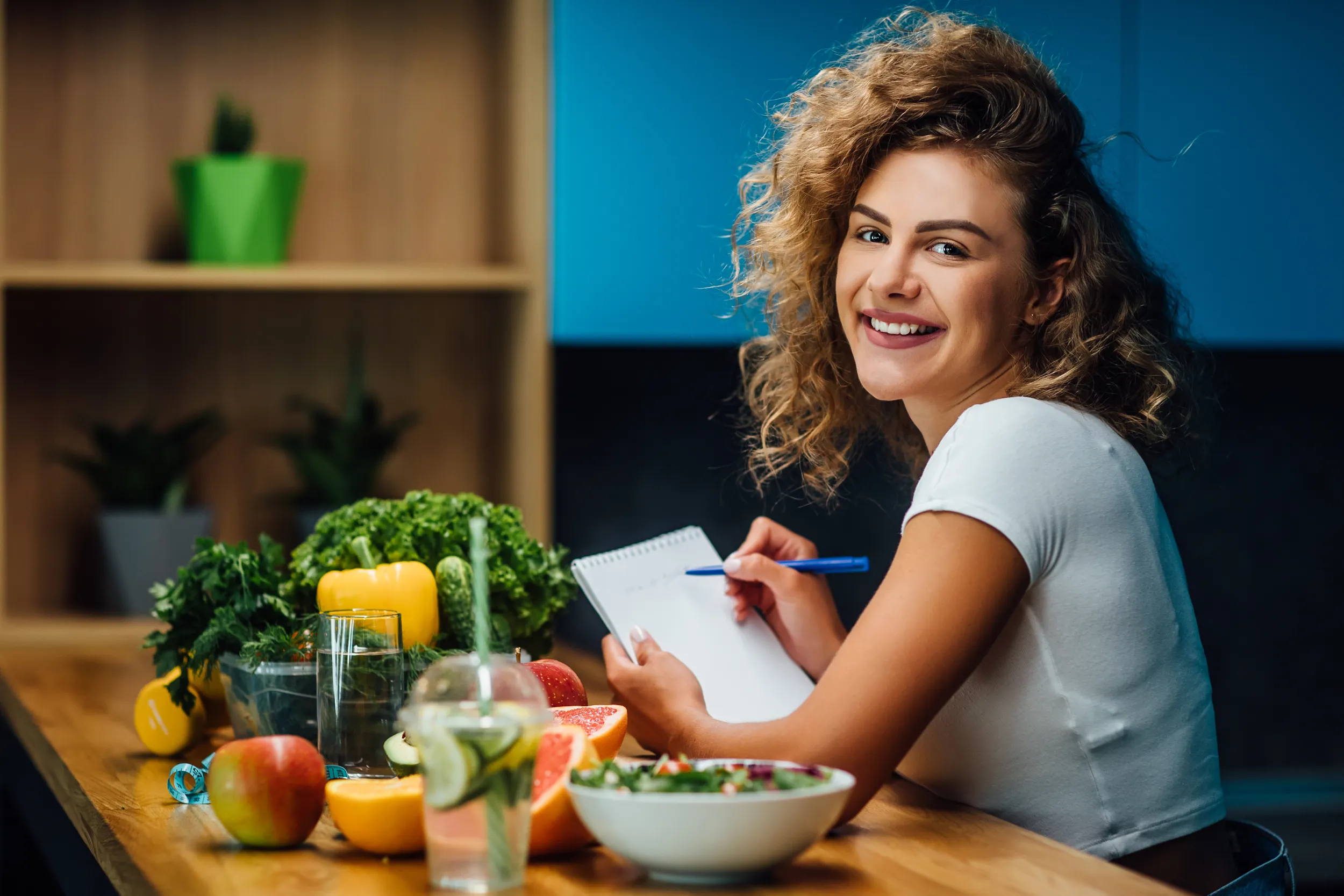 Eine Ernährungsberaterin macht sich Notizen an einem Tisch mit buntem Obst und Gemüse