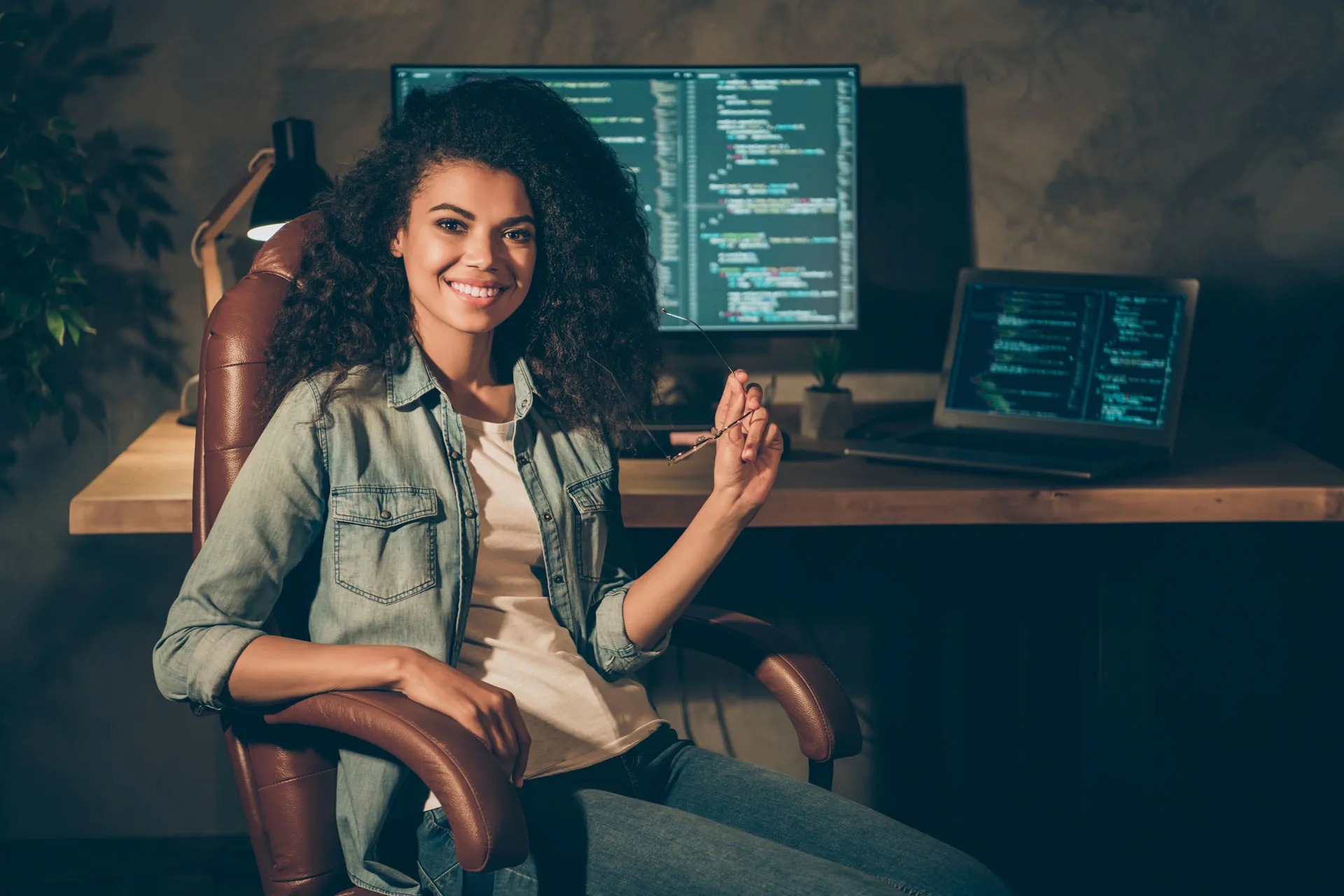 Frau, die an einem Laptop und einem grossen Bildschirm eine Webseite programmiert.